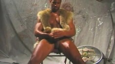 Black gladiator stud sits on his chair and chokes the life out of his prick